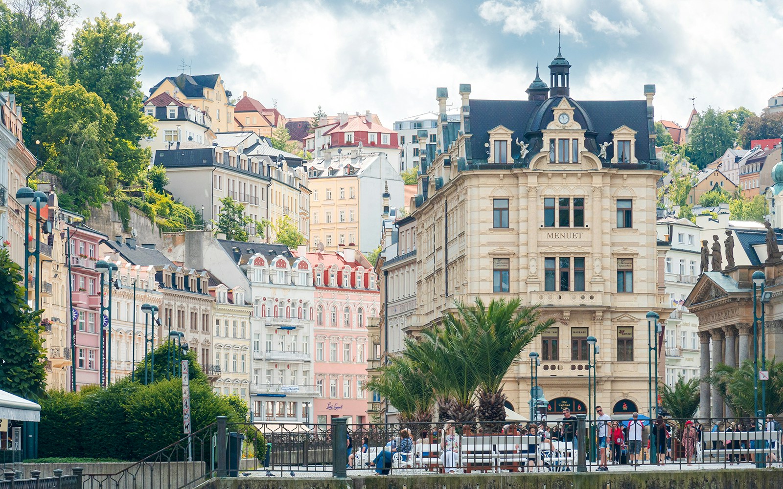 Historic buildings and Market Colonnade in Prague with colorful facades and lush greenery.