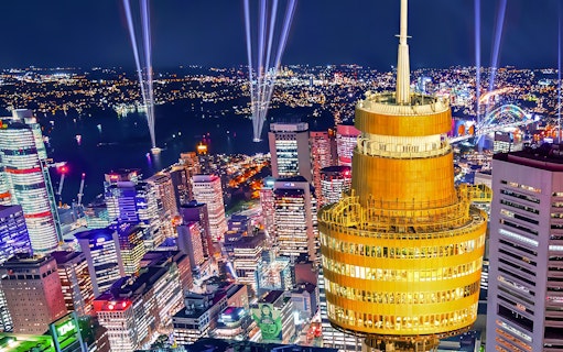 Sydney skyline at night featuring illuminated Sydney Tower and city lights.