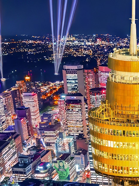 Sydney skyline at night featuring illuminated Sydney Tower and city lights.