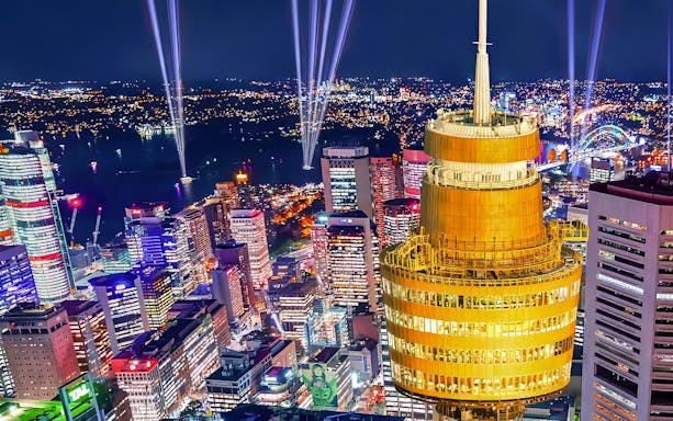 Sydney skyline at night featuring illuminated Sydney Tower and city lights.