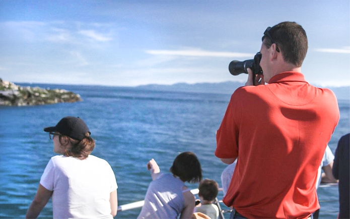 Tourists on a boat photographing wildlife during Seattle whale watching tour.