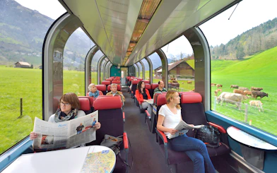 Passengers enjoying scenic view from panoramic train window in Swiss countryside.