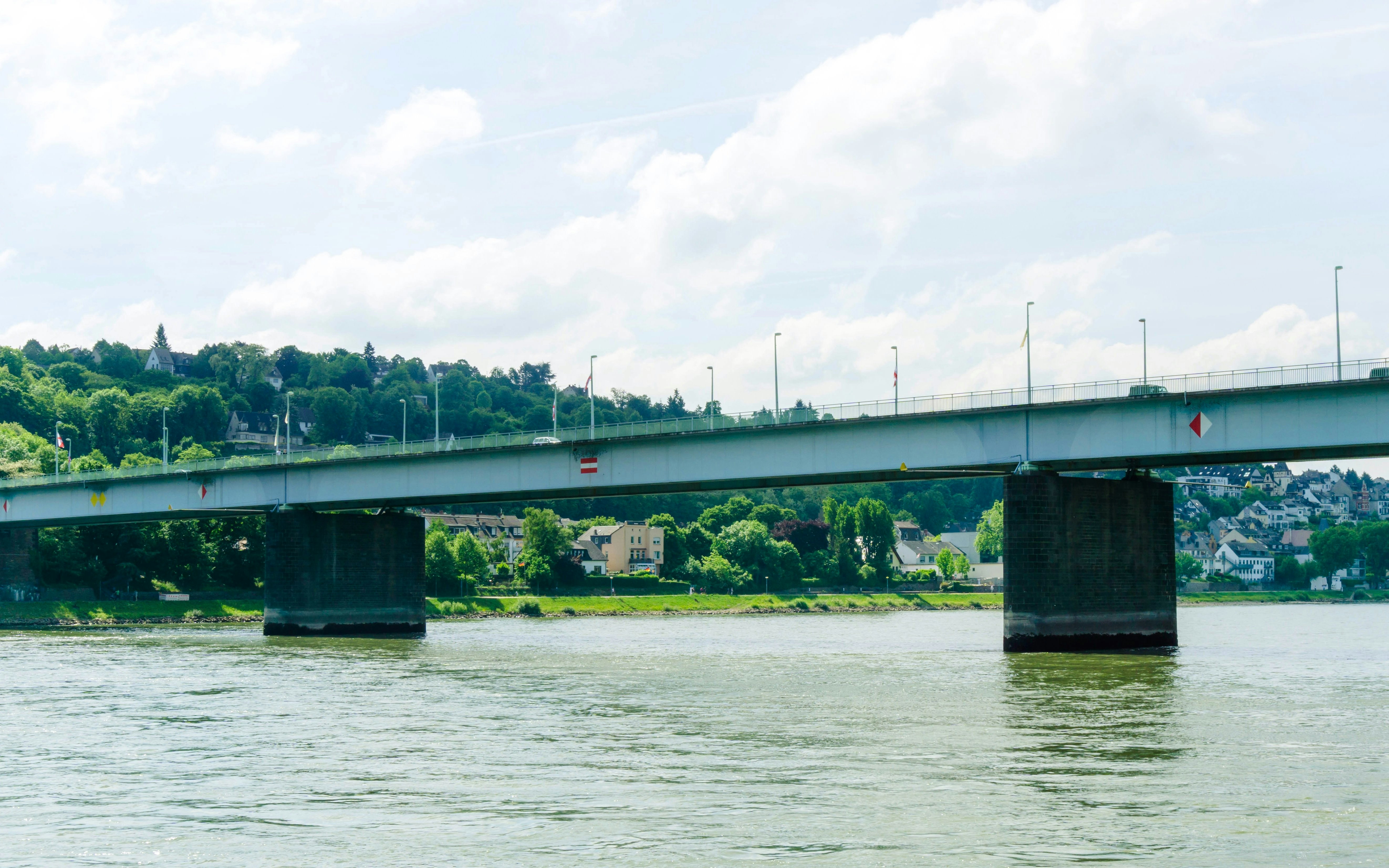 Pfaffendorfer Bridge spanning the Rhine River in Koblenz, Germany, with lush greenery in the background.