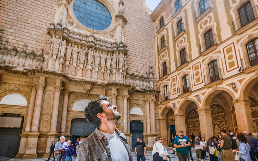 Tourists exploring the courtyard of Montserrat Monastery, admiring the architecture.