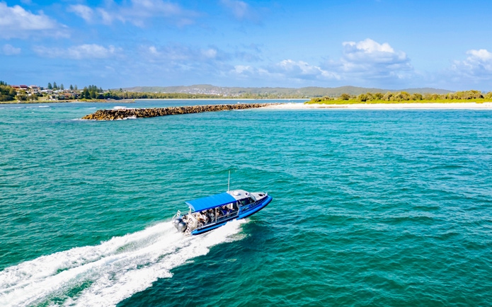 Boat with people cruising along the coast of Lake Macquarie, Australia.
