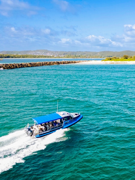 Boat with people cruising along the coast of Lake Macquarie, Australia.