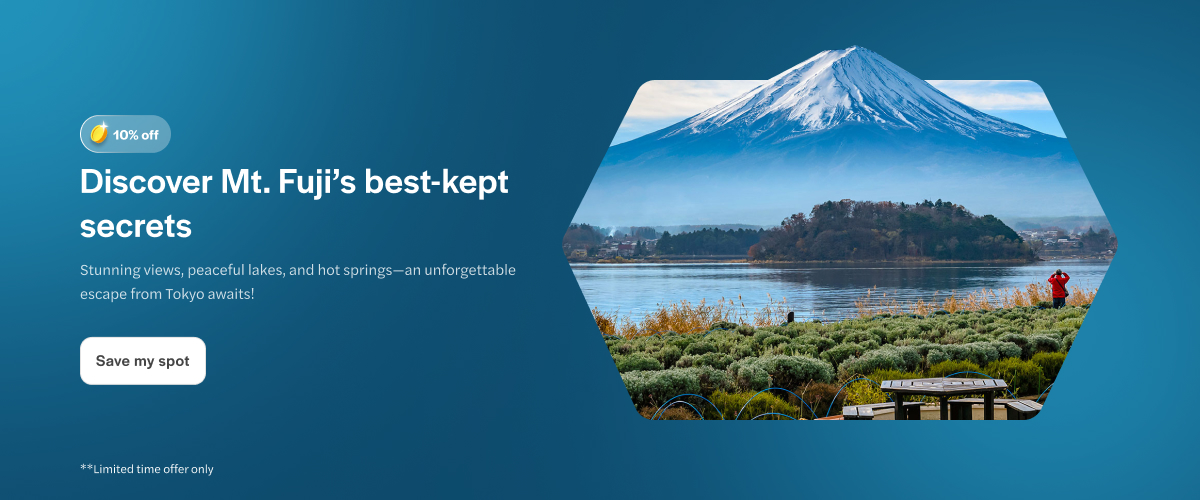 Mt. Fuji view over a serene lake with a person taking photos.