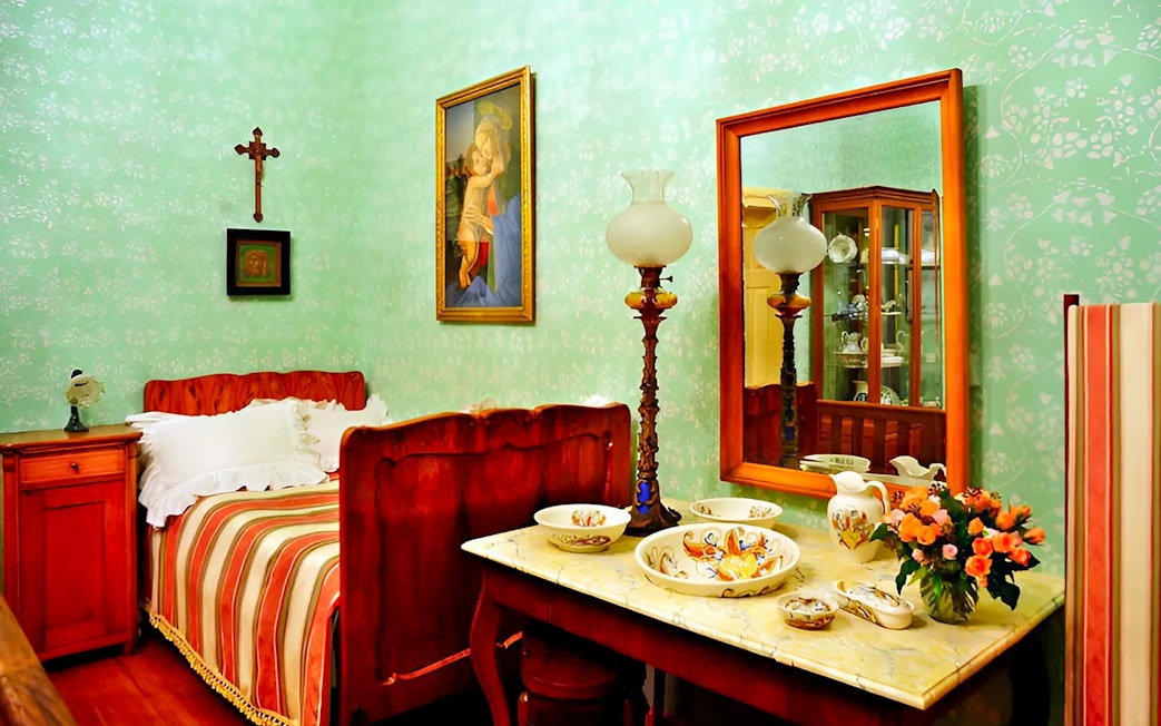 Cesky Krumlov Castle interior with vintage bed, ornate tableware, and artwork.