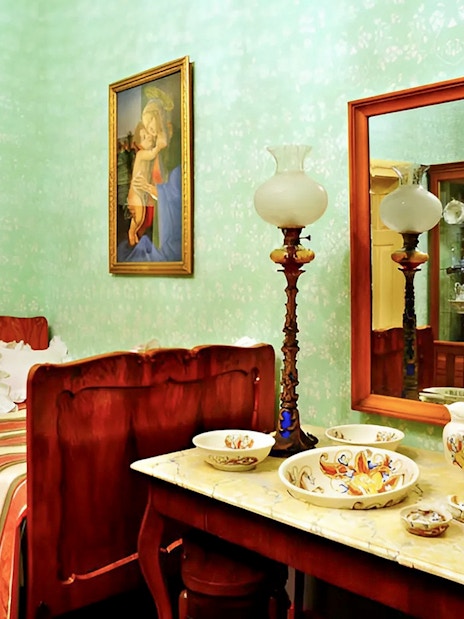 Cesky Krumlov Castle interior with vintage bed, ornate tableware, and artwork.