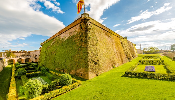 Montjuic Castle with lush gardens and Catalonia flag, Barcelona.