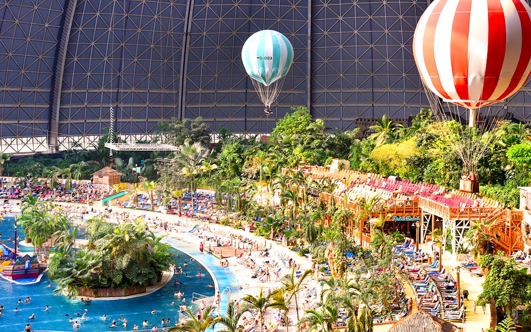 Tropical Islands Resort indoor beach with palm trees and hot air balloons.