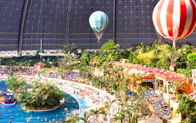Tropical Islands Resort indoor beach with palm trees and hot air balloons.