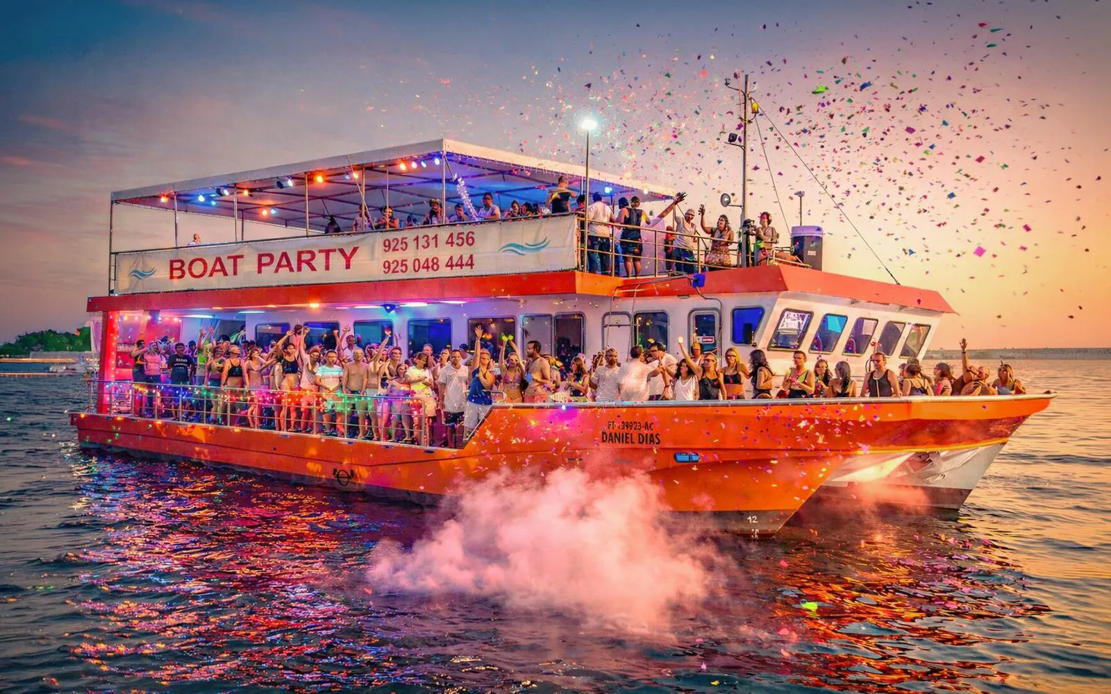 Lisbon boat party cruise with DJ, open bar, and people celebrating at sunset.