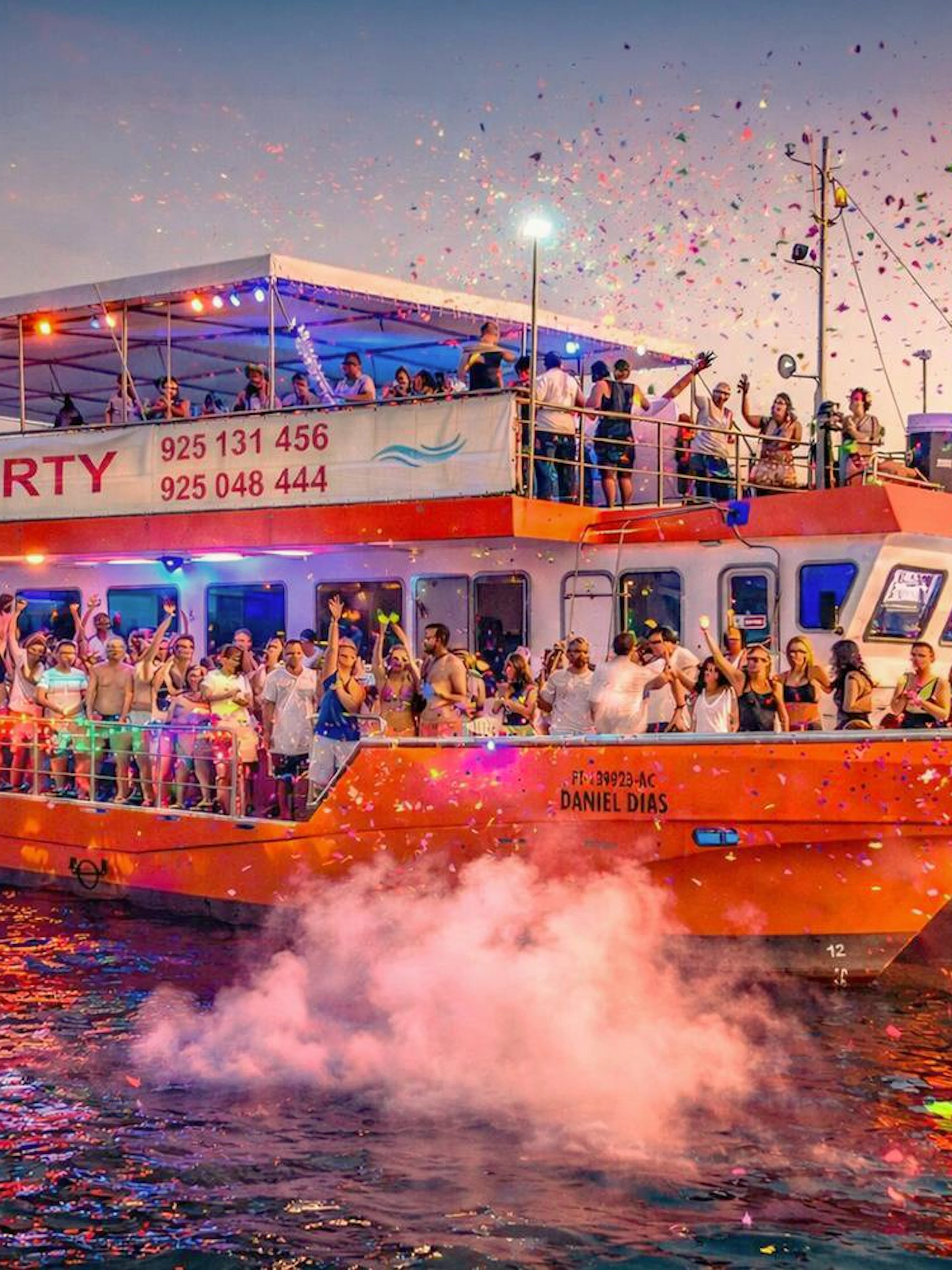 Lisbon boat party cruise with DJ, open bar, and people celebrating at sunset.