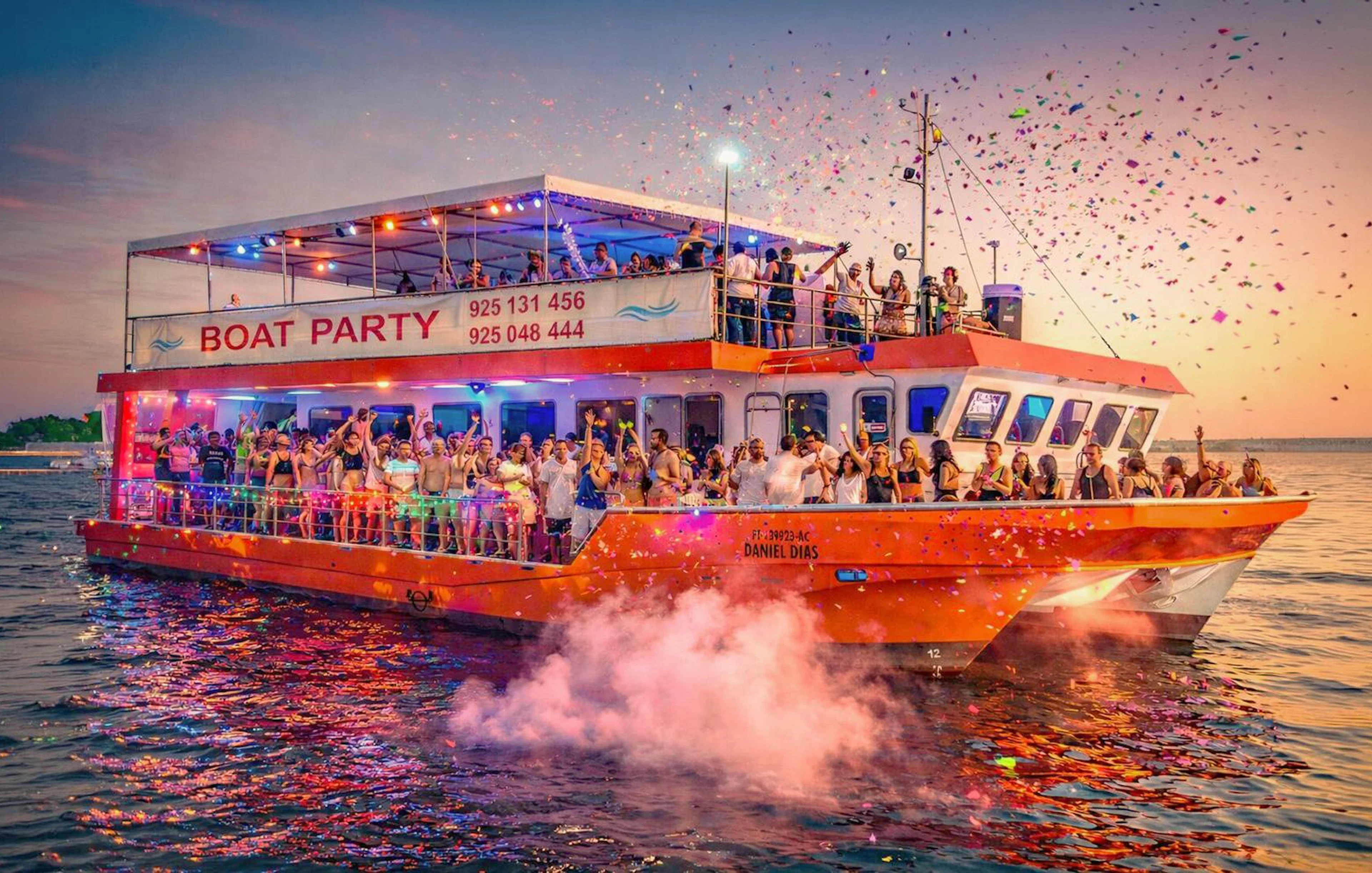 Lisbon boat party cruise with DJ, open bar, and people celebrating at sunset.