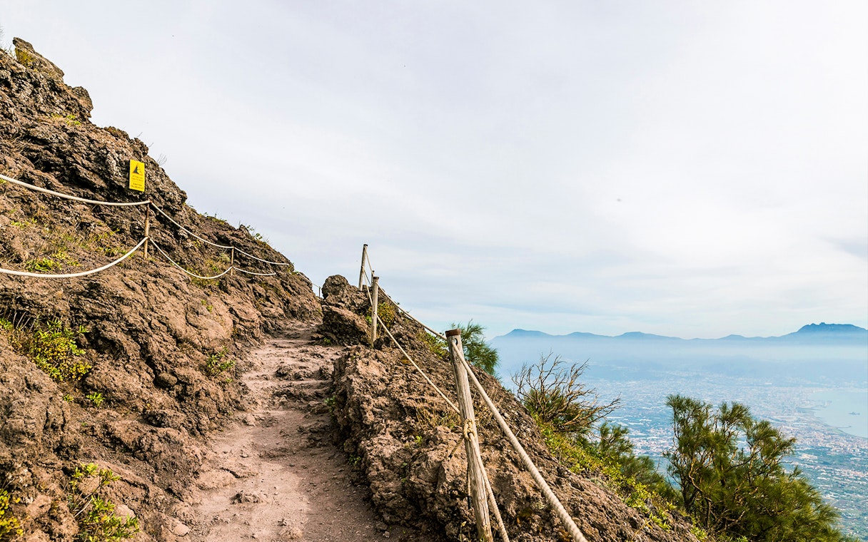 Rocky path on Mount Vesuvius with view of Naples in the distance.