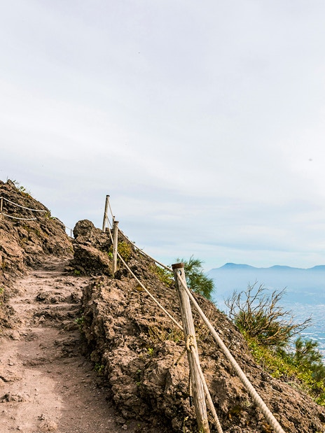 Rocky path on Mount Vesuvius with view of Naples in the distance.