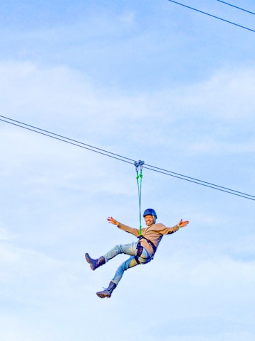 Person ziplining on Xline Dubai against a clear sky.
