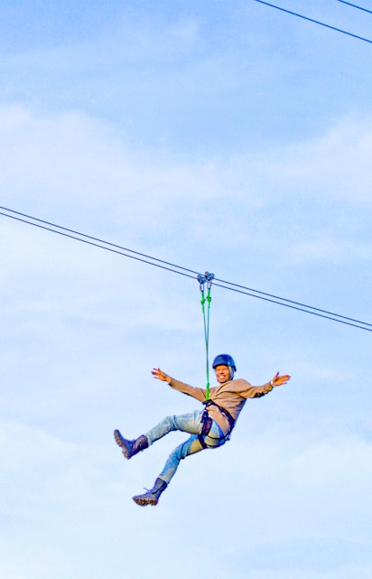 Person ziplining on Xline Dubai against a clear sky.