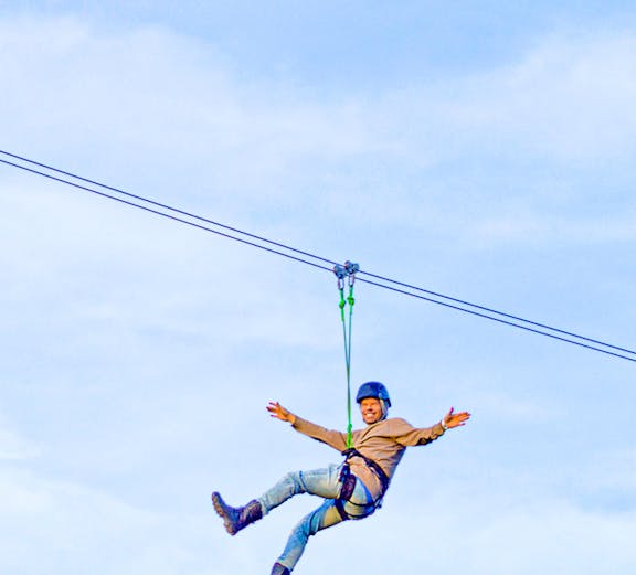 Person ziplining on Xline Dubai against a clear sky.