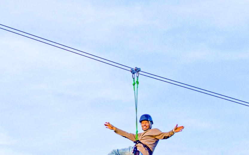 Person ziplining on Xline Dubai against a clear sky.