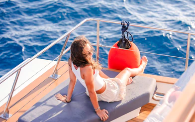Person relaxing on a catamaran deck during a sunset cruise with ocean view.