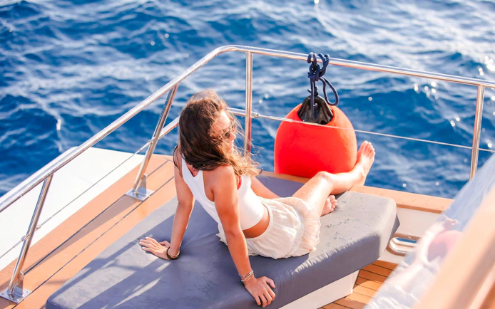 Person relaxing on a catamaran deck during a sunset cruise with ocean view.