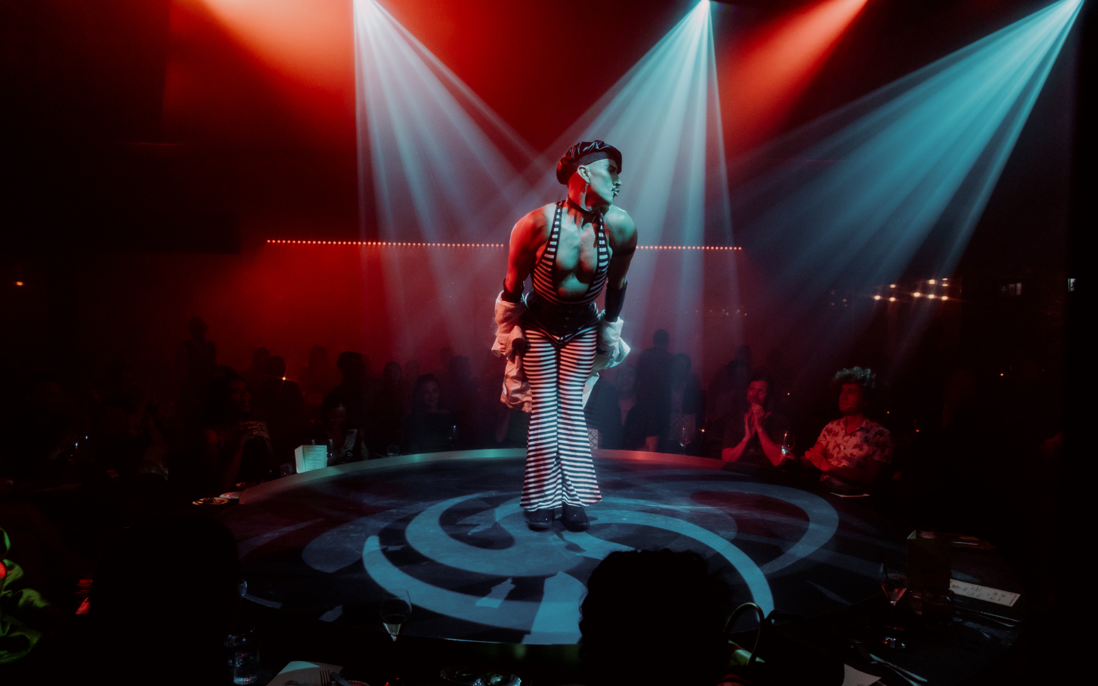 Performer on stage at The Emerald Room with colorful lights and audience.