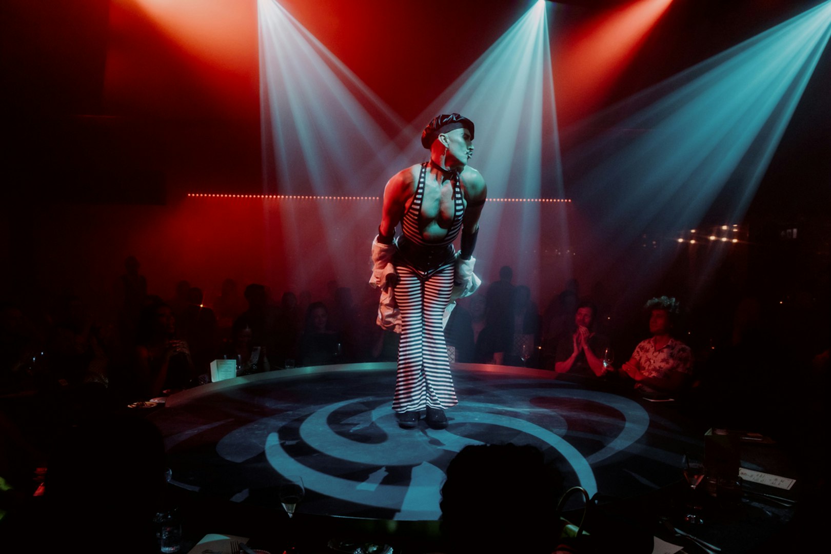 Performer on stage at The Emerald Room with colorful lights and audience.