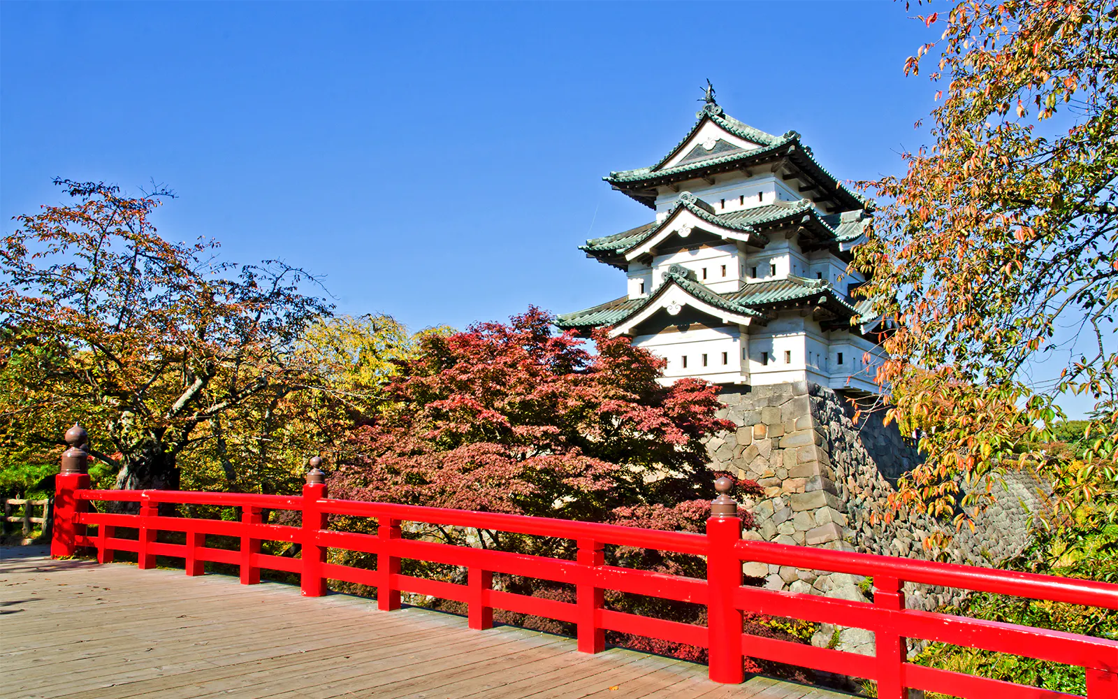 Hirosaki Castle with red bridge and autumn foliage in Japan.