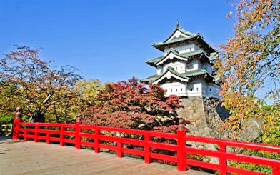 Hirosaki Castle with red bridge and autumn foliage in Japan.
