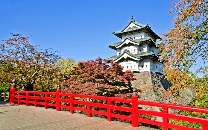 Hirosaki Castle with red bridge and autumn foliage in Japan.