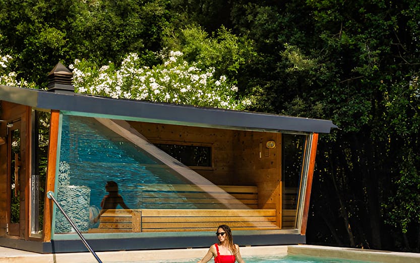 Woman enjoying outdoor pool at QC Termeroma spa surrounded by lush greenery.