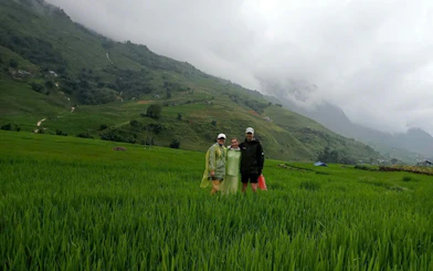 Tourists in raincoats standing in lush rice terraces of Mu Cang Chai, Vietnam.