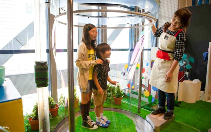 Children and guide inside bubble-making exhibit at Kids Plaza Osaka.
