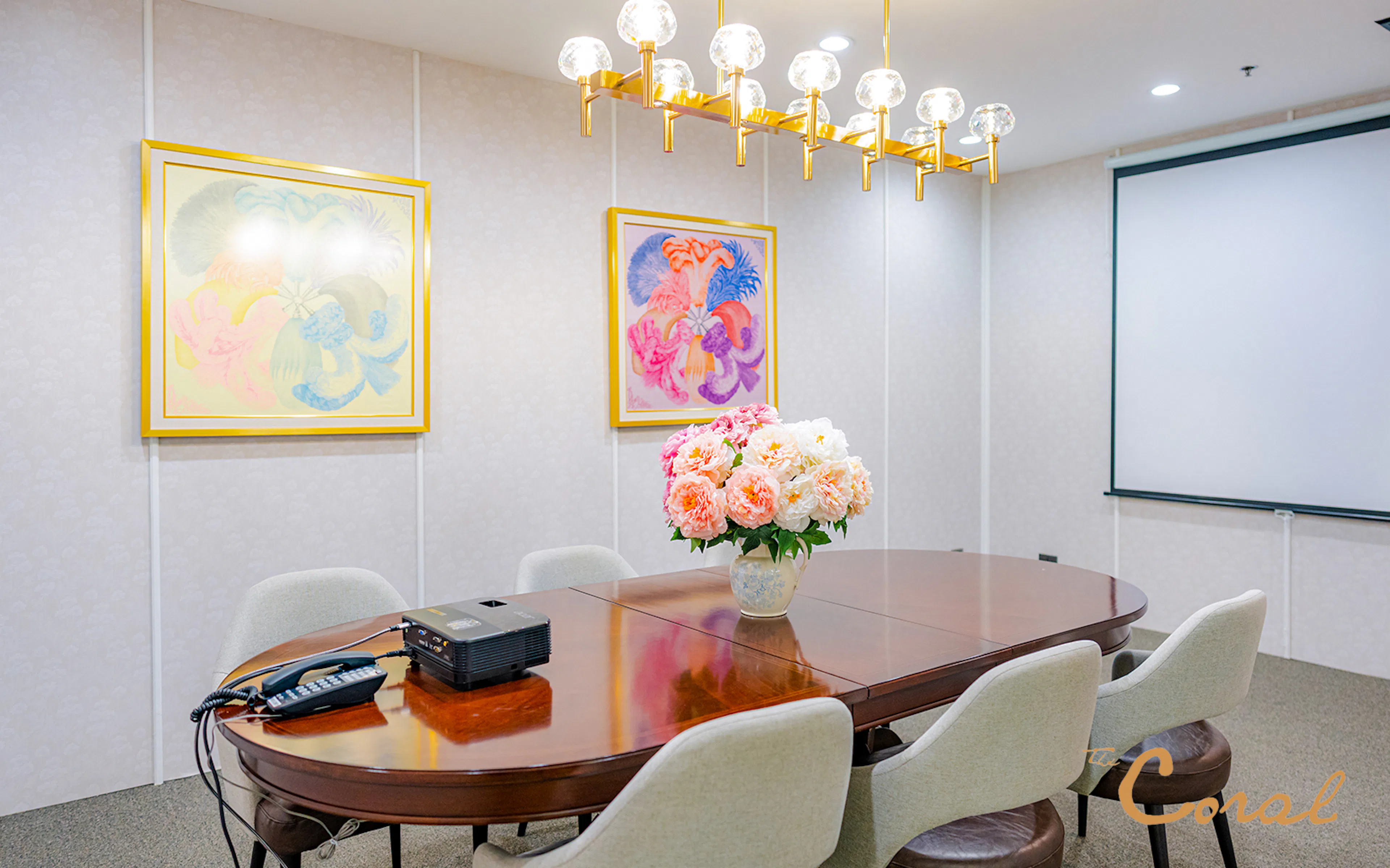 Meeting room with floral centerpiece and projector at Coral Finest Business Class Lounge, Bangkok airport.