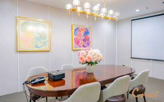 Meeting room with floral centerpiece and projector at Coral Finest Business Class Lounge, Bangkok airport.
