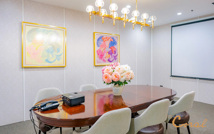 Meeting room with floral centerpiece and projector at Coral Finest Business Class Lounge, Bangkok airport.