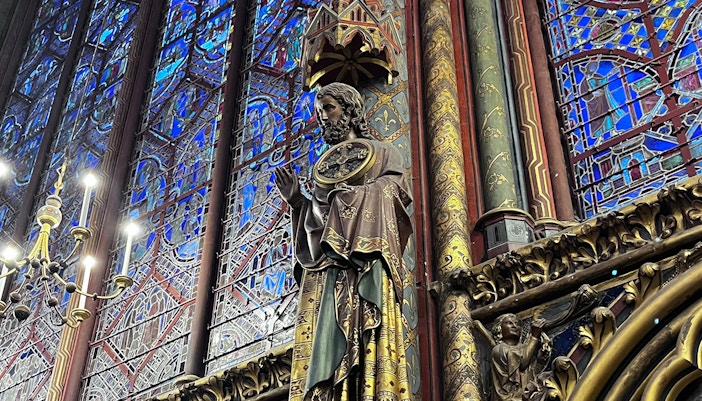 Sainte Chapelle interior with stained glass windows and statue.