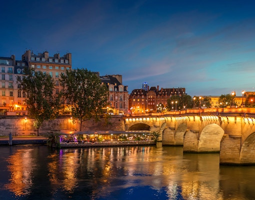 Île de la Cité illuminated at night with Seine River reflections, Paris, France.