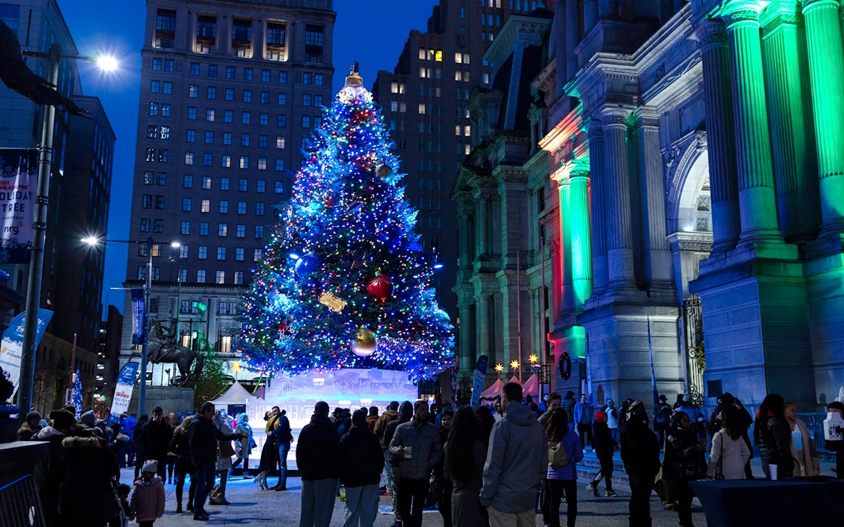 Holiday lights tour in Philadelphia with a large decorated Christmas tree and people gathered around.