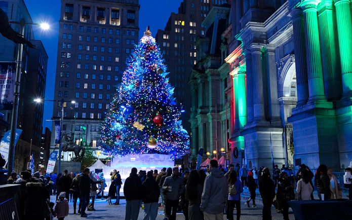 Holiday lights tour in Philadelphia with a large decorated Christmas tree and people gathered around.