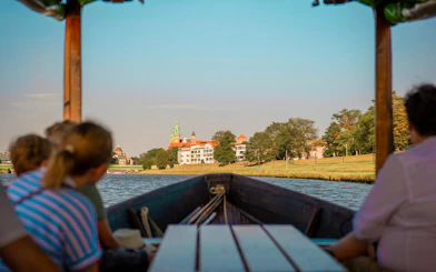 Boat on Vistula River with view of historic buildings in the distance.