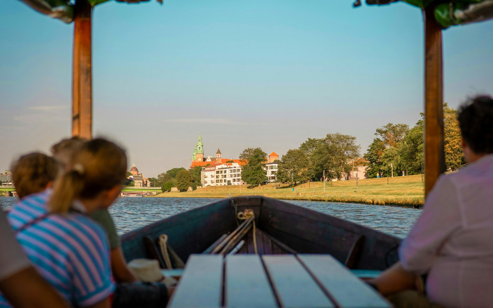Boat on Vistula River with view of historic buildings in the distance.