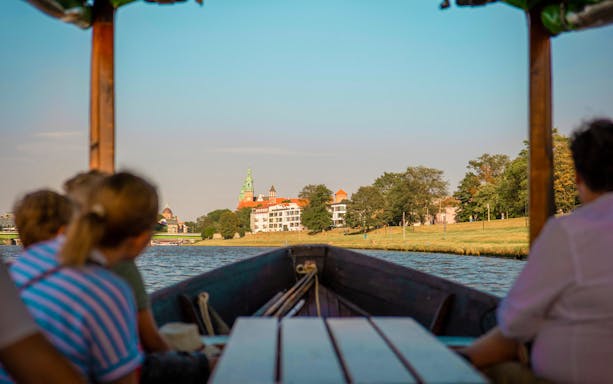 Boat on Vistula River with view of historic buildings in the distance.