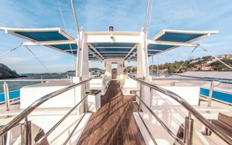 Cruise boat deck with seating, sailing near Rio's coastline.