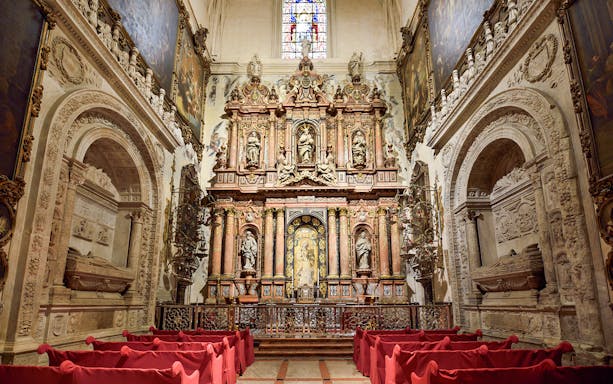 Royal Chapel interior with ornate altar and red seating, Seville Cathedral.