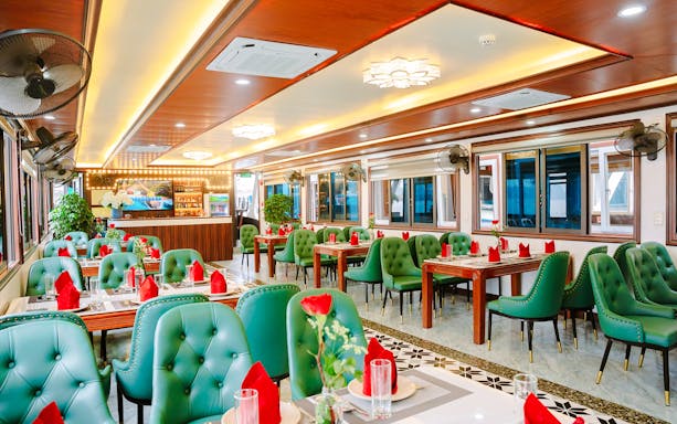 Dining area on a Ha Long Bay cruise boat with green chairs and red napkins.