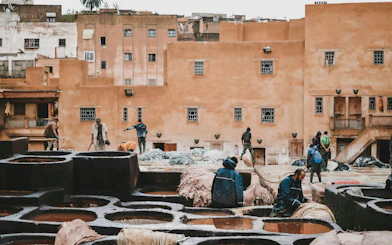Workers at traditional tannery in Fes Old Medina, Morocco, surrounded by dyeing vats.