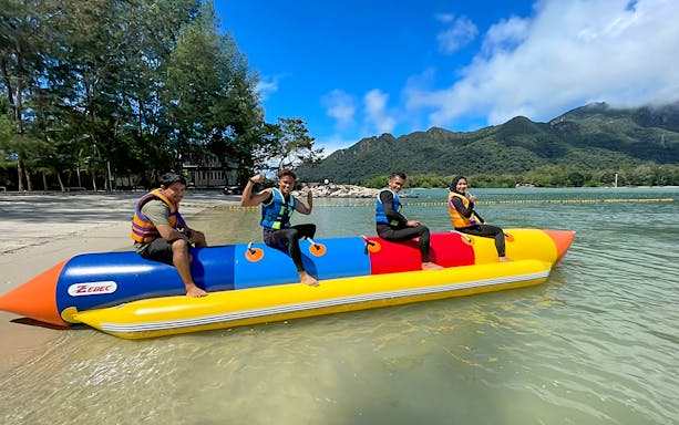 People enjoying a banana boat ride at Paradise 101 with lush mountains in the background.